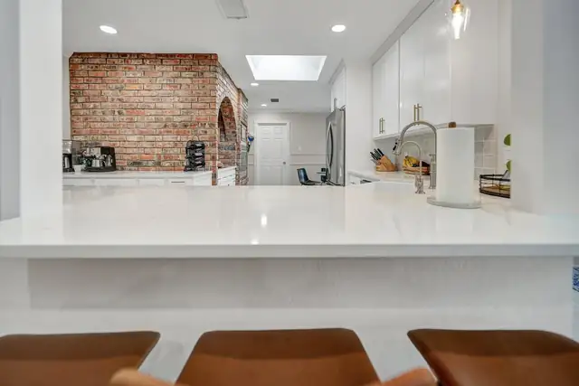 Ryburn Residence remodel in Midland with an exposed brick wall, white quartz peninsula and skylight
