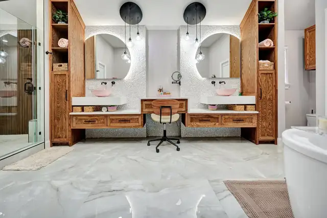Castor Residence bathroom in Midland with a double vanity and makeup desk, round backlit mirrors, wood storage towers and a freestanding tub