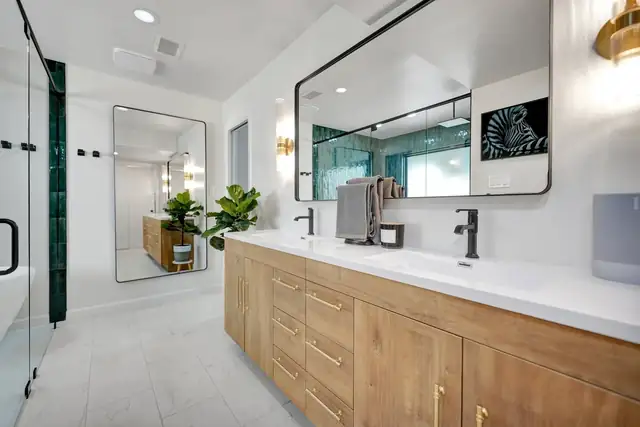 Driftwood Residence bathroom in Midland with a long wood vanity, white quartz top, black-framed mirror and walk-in glass shower