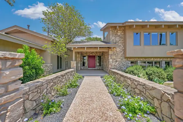 Teakwood Residence exterior in Midland with stone garden walls, a gravel walkway and a red front door