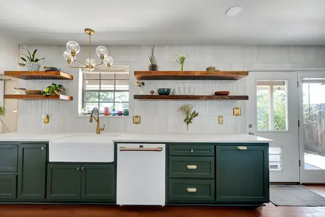 Wydewood Residence kitchen with green shaker cabinets, a white farmhouse sink, floating wood shelves and a brass chandelier
