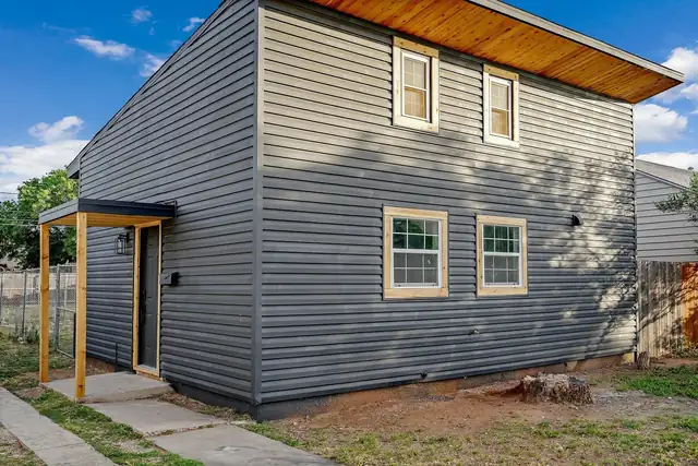 Michigan Residence in Midland after Alpha's whole-home remodel, with new gray siding, wood-trimmed windows and a covered entry