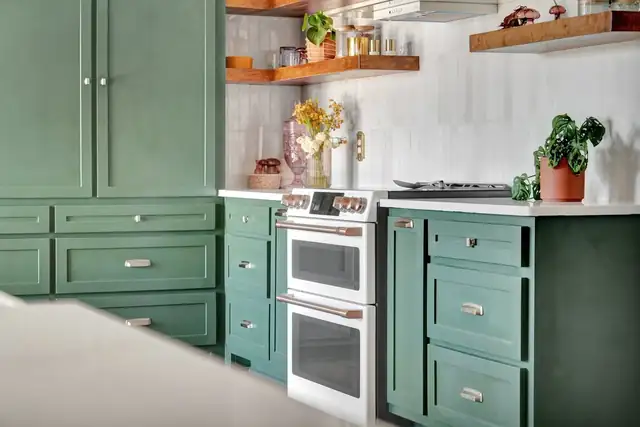Wydewood Residence kitchen in Midland with green shaker cabinets, floating wood shelves, white tile and a double-oven range